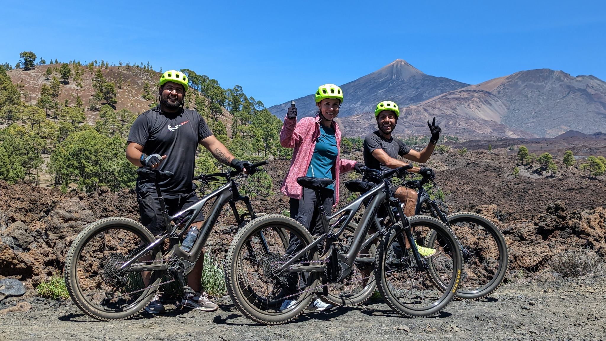 Three smiling e-bike riders with Teide volcano behind them